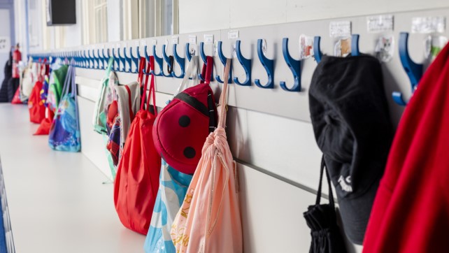 Coats and bags hung up on pegs in a primary school 
