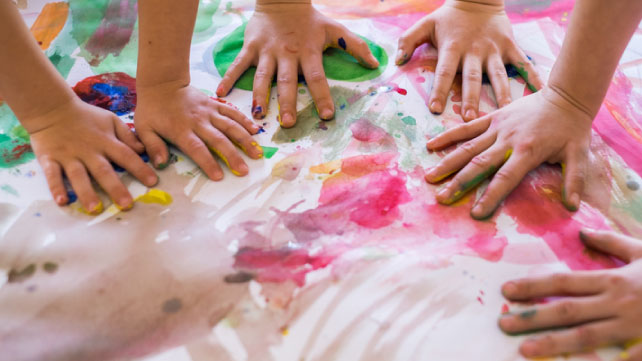 Childrens hands in water paints on table