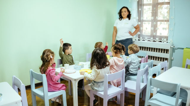  teacher with group of children on a lunch break at preschool